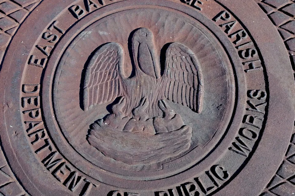 Close-up of metal manhole cover with pelican logo and 'East Baton Rouge Parish Department of Public Works.'